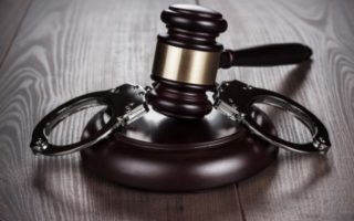 handcuffs and judge gavel on the brown wooden table